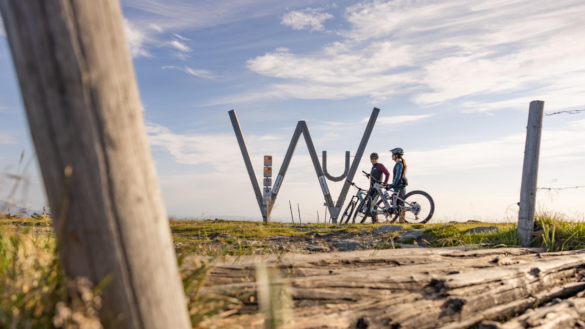 Zwei Mountainbiker auf den Wexl-Trails mit Bilderungstafeln und Aussicht