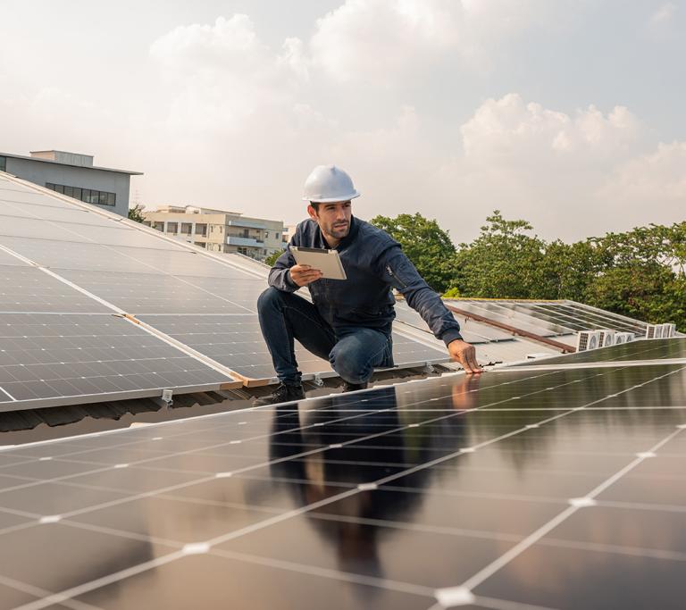 Mann arbeitet auf Photovoltaik Anlage
