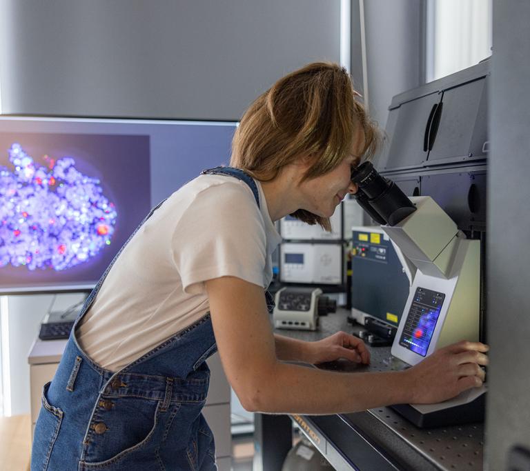 Junge Forscherin blickt durchs Mikroskop