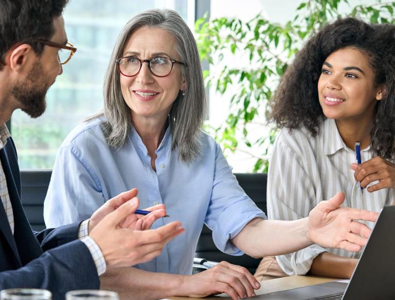 Drei Personen in einer Besprechung und mit aufgeklappten Laptop