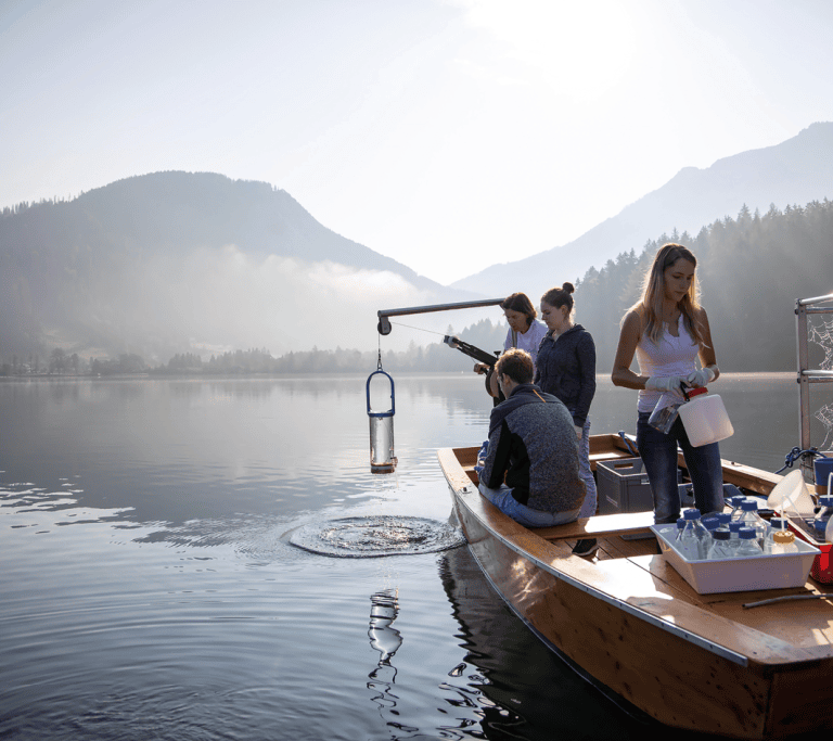 Forschende entnehmen auf einem See Wasserproben von einem Boot aus