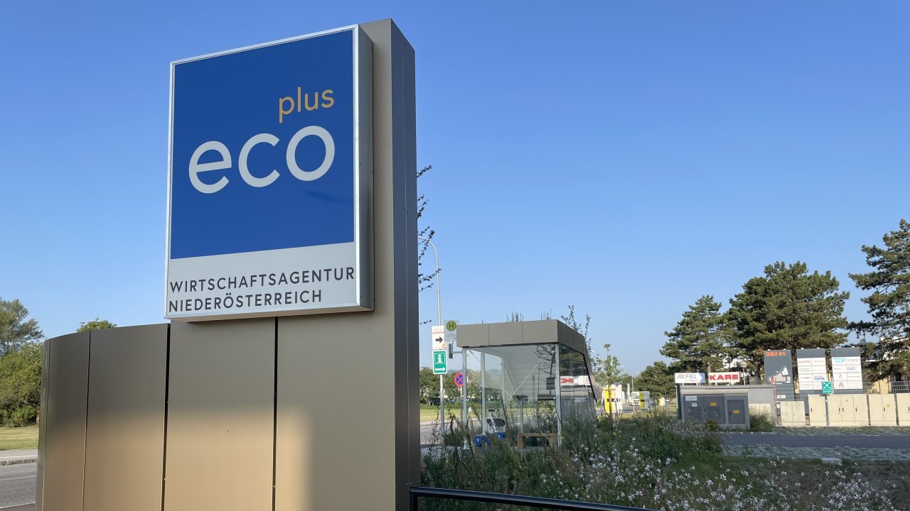 Einfahrtsbereich zu Firmengebäude von ecoplus mit Logo und Bushaltestelle