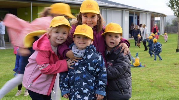 IZIBIZI kids corner Kinder im Garten mit gelben IZIBIZI Kappen