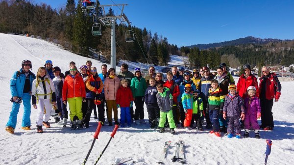Gruppenfoto mit Skifahrern im Schnee unterhalb eines Sesselliftes