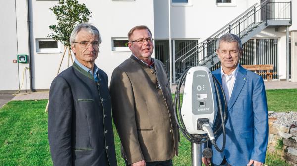 drei Personen stehen nebeneinander und präsentieren eine E Tankstelle