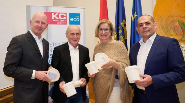 vier Personen stehen nebeneinander und lachen in die Kamera