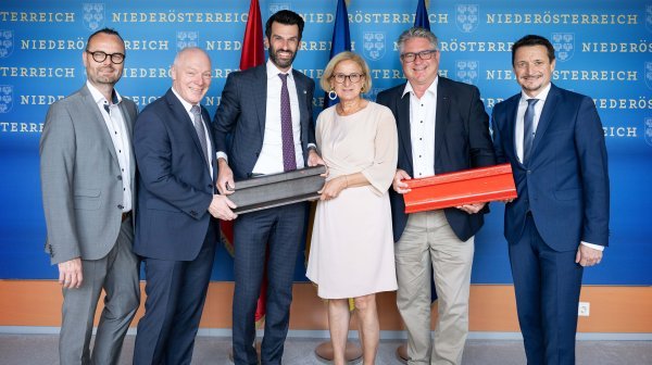 Gruppenfoto mit sechs Personen die 2 kleine Schienenstücke vor einer Niederösterreich-Rückwand in die Kamera halten