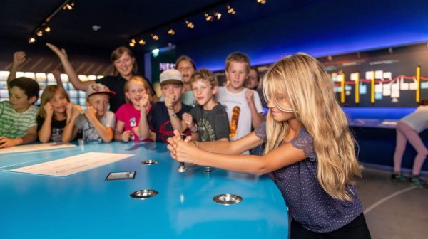 viele Kinder stehen rund um einen Tisch