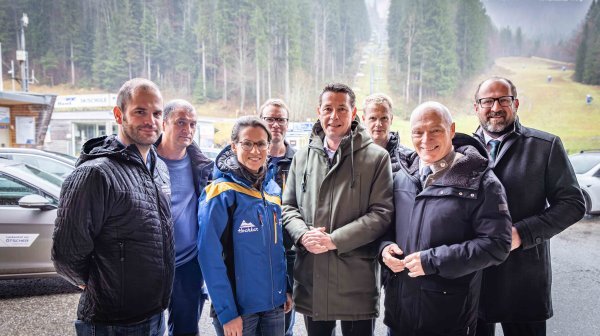 Acht Personen stehen im Freien vor der noch grünen Piste der Ötscherlifteackenhofer