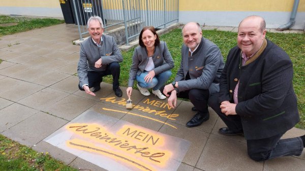 vier Personen hocken nebeneinander und zeigen auf den Schriftzug "Mein Weinviertel"