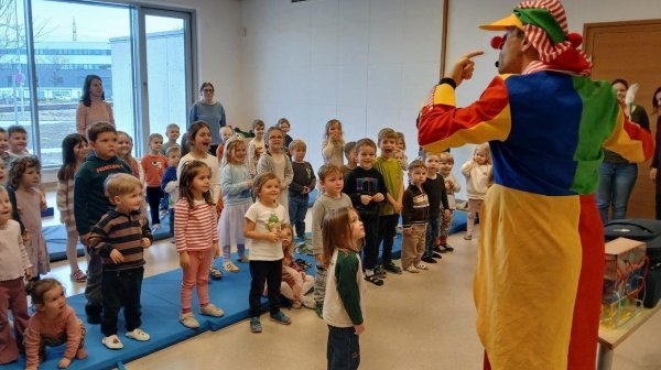 Verkleideter Clown Lucky macht Späße vor einer Kindergartengruppe