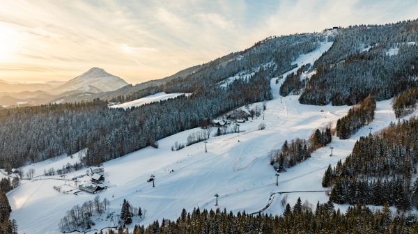 Drohnenansicht auf beschneites Skigebiet in Abendstimmung