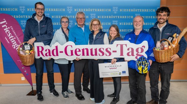 Sieben Personen stehen vor einer blauen Wand.