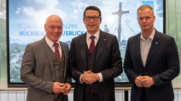 Drei Personen stehen vor Display mit Bergfoto