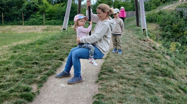 Kindergartenkinder mit Betreuerin auf einer Seilrutsche am Spielplatz