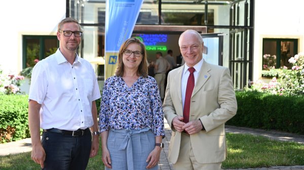 Foto von drei Personen vor einem Gebäude