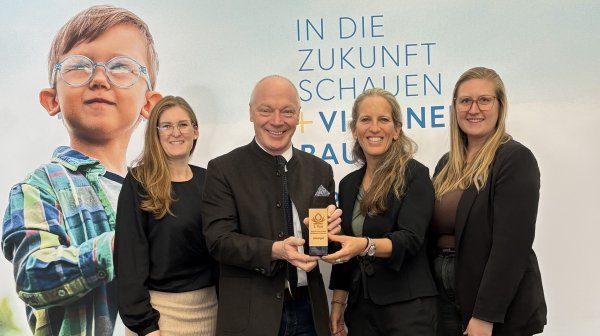 Vier Perosnen halten einen kleinen hölzernen Award vor einer ecoplus Rückwand in die Kamera
