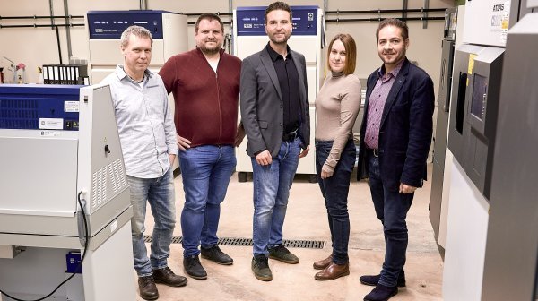 Fünf Personen stehen bei 3D-Druckern