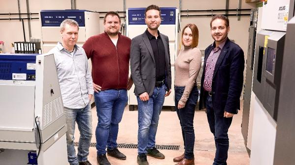 Fünf Personen stehen bei 3D-Druckern