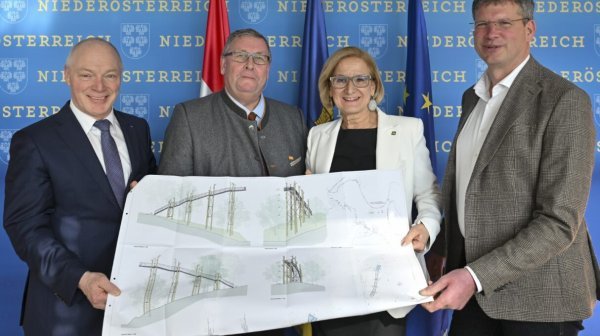 Vier Personen halten einen Bauplan