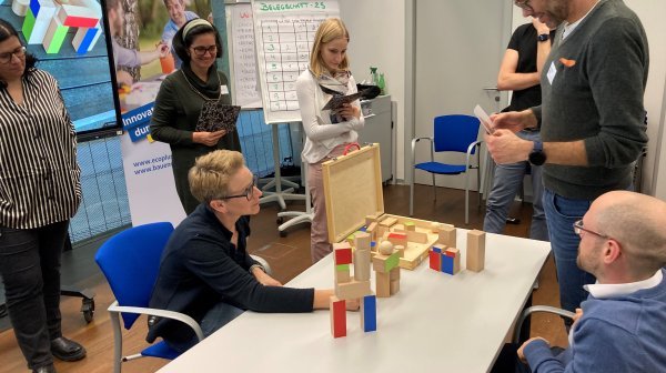 Personen um Tisch versammelt mit Spiel