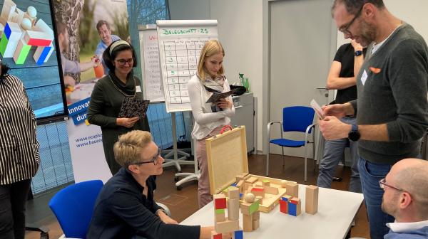 Personen um Tisch versammelt mit Spiel