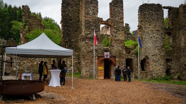 Steinmauern und seitlich steht ein kleines weißes Zelt, wo mehrere Personen darunter stehen