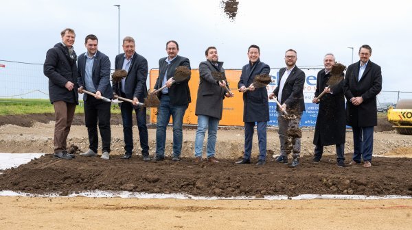 Große Männergruppe direkt beim Spatenstich mit Spaten in der Hand