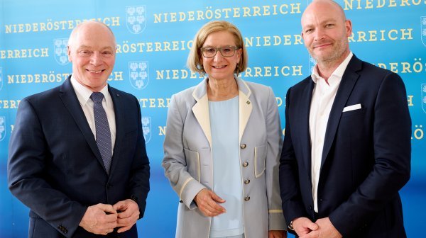 Drei Personen stehen vor eine Standsystem mit ganz vielen Niederösterreich-Schriftzügen