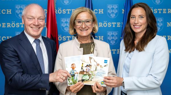 Drei Personen halten Broschüren