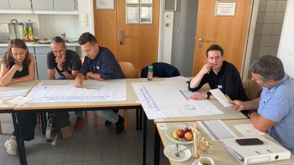 Personen sitzen an Tischen beim Workshop