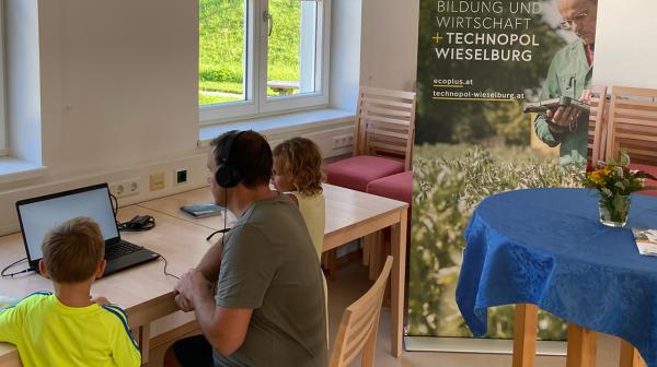 Mann sitzt mit zwei Kindern vor einem Laptop