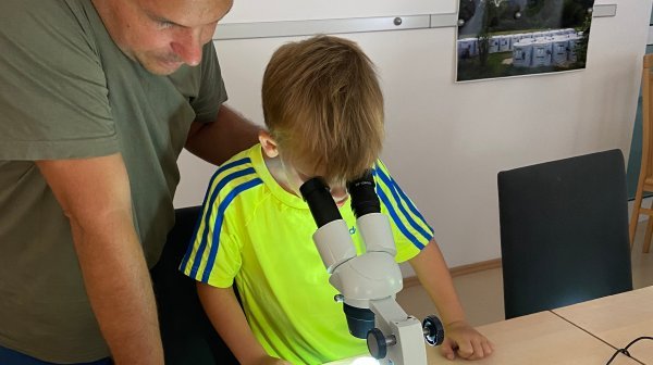 Bursch schaut durch Mikroskop beim Tag der offenen Tür - Wassercluster Lunz