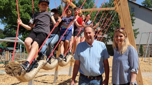 zwei Leute stehen nebeneinander und im Hintergrund spielen Kinder