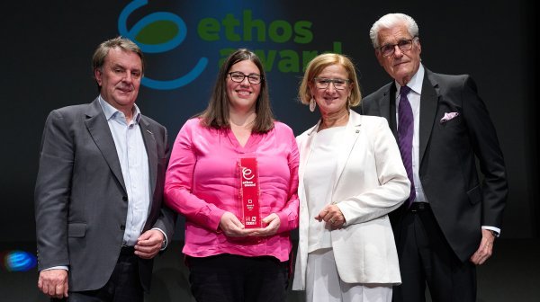 Vier Leute stehen in einer Reihe und halten einen Award