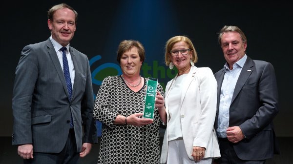 Vier Leute stehen in einer Reihe mit einem Award