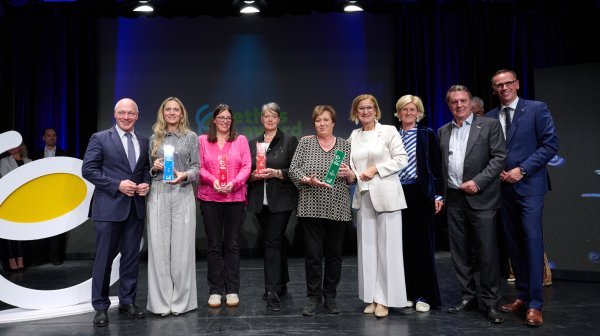 Acht Leute stehen in einer Reihe mit Awards