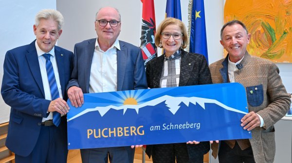 vier Personen stehen nebeneinander und halten ein Schild in die Kamera