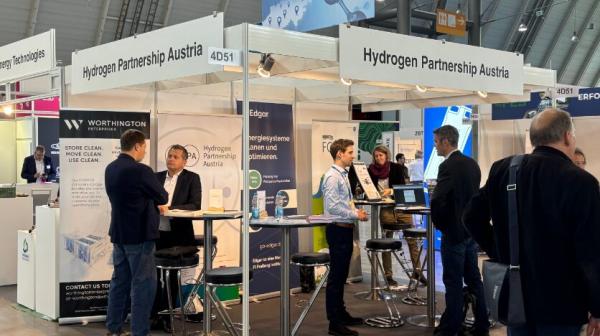 Personen stehen um einen Messestand herum