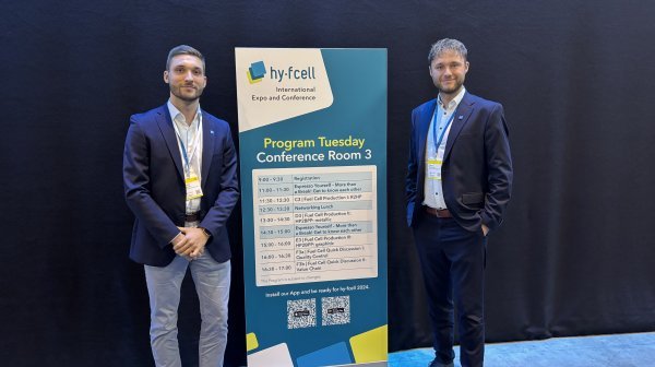 zwei Personen stehen neben einem Roll Up 